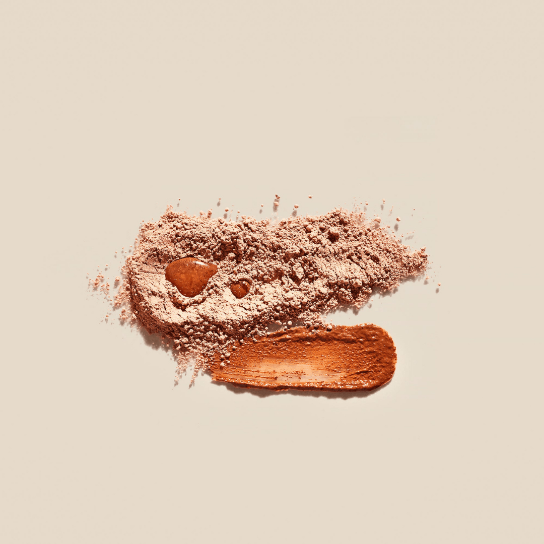 Palermo Body’s Vitamin C Facial Mask is displayed with loose powder and bronze-brown makeup on a light beige background, highlighting the radiant texture revealed by gentle exfoliation or a Vitamin C treatment.