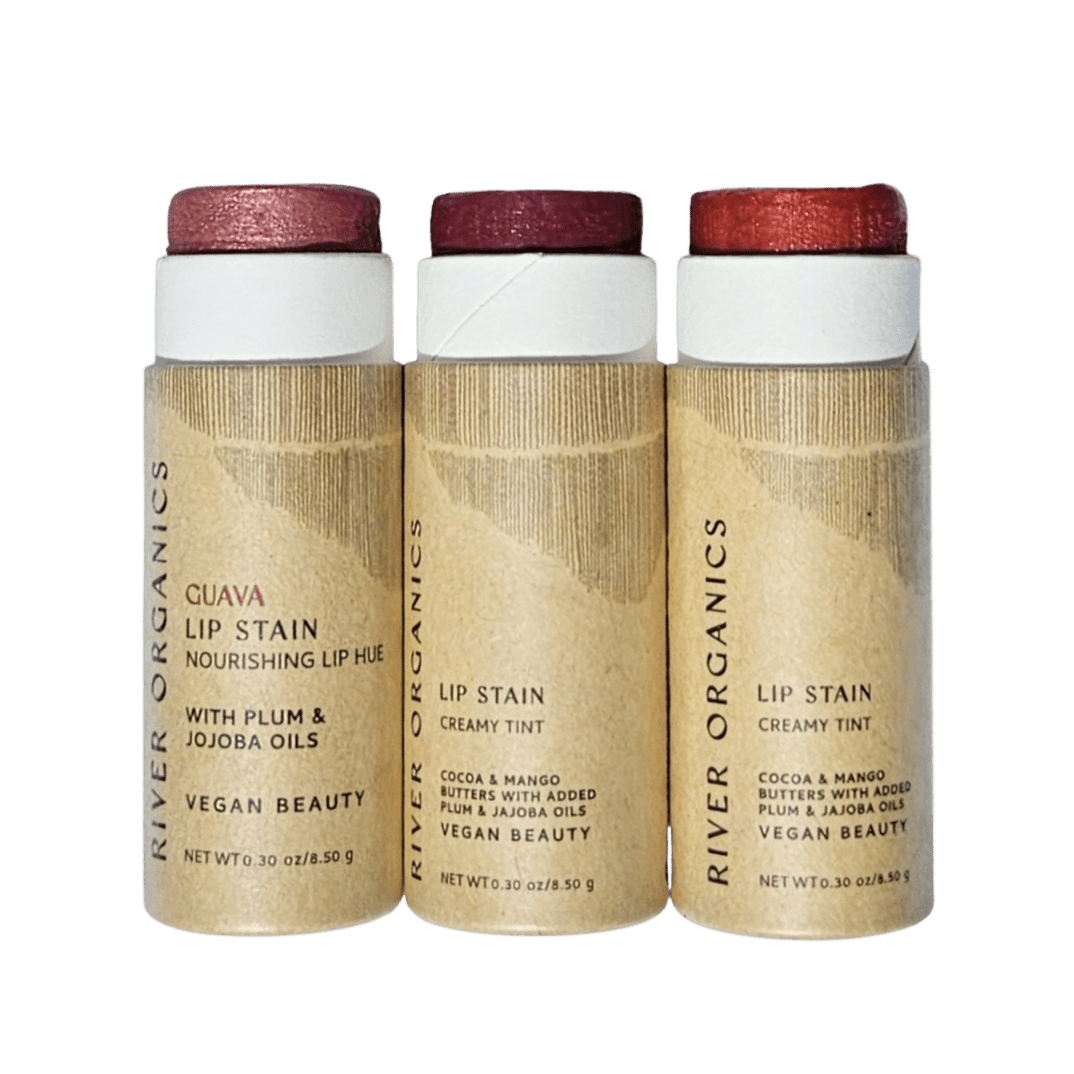 River Organics Lip Stain Sets come in upright cardboard tubes, featuring shades from light pink to deep red. Labels highlight nourishing oils and vegan ingredients; one organic lip stain is named “Guava.”.