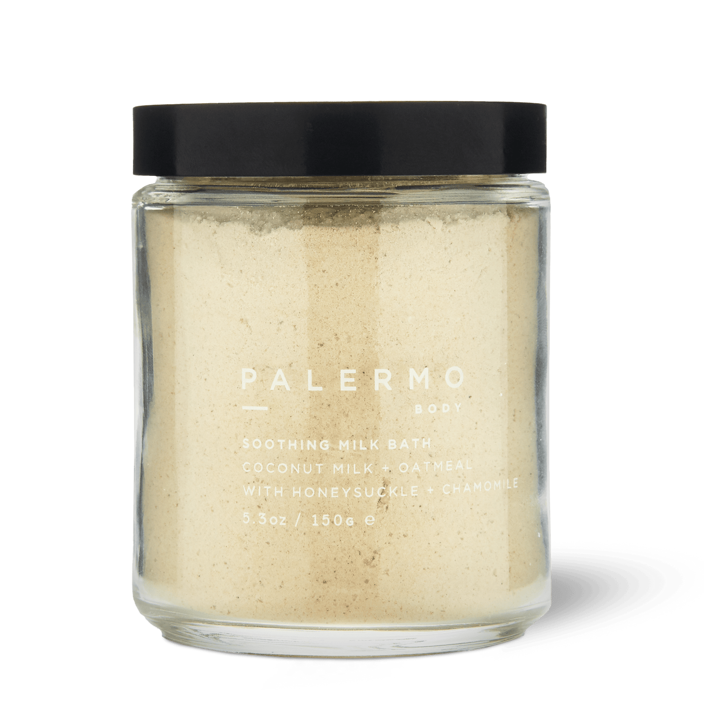 Palermo Body Soothing Milk Bath is a 5.3 oz clear glass jar with a black lid, containing light beige powder made with coconut milk, oatmeal, honeysuckle, and chamomile for soothing skin care.