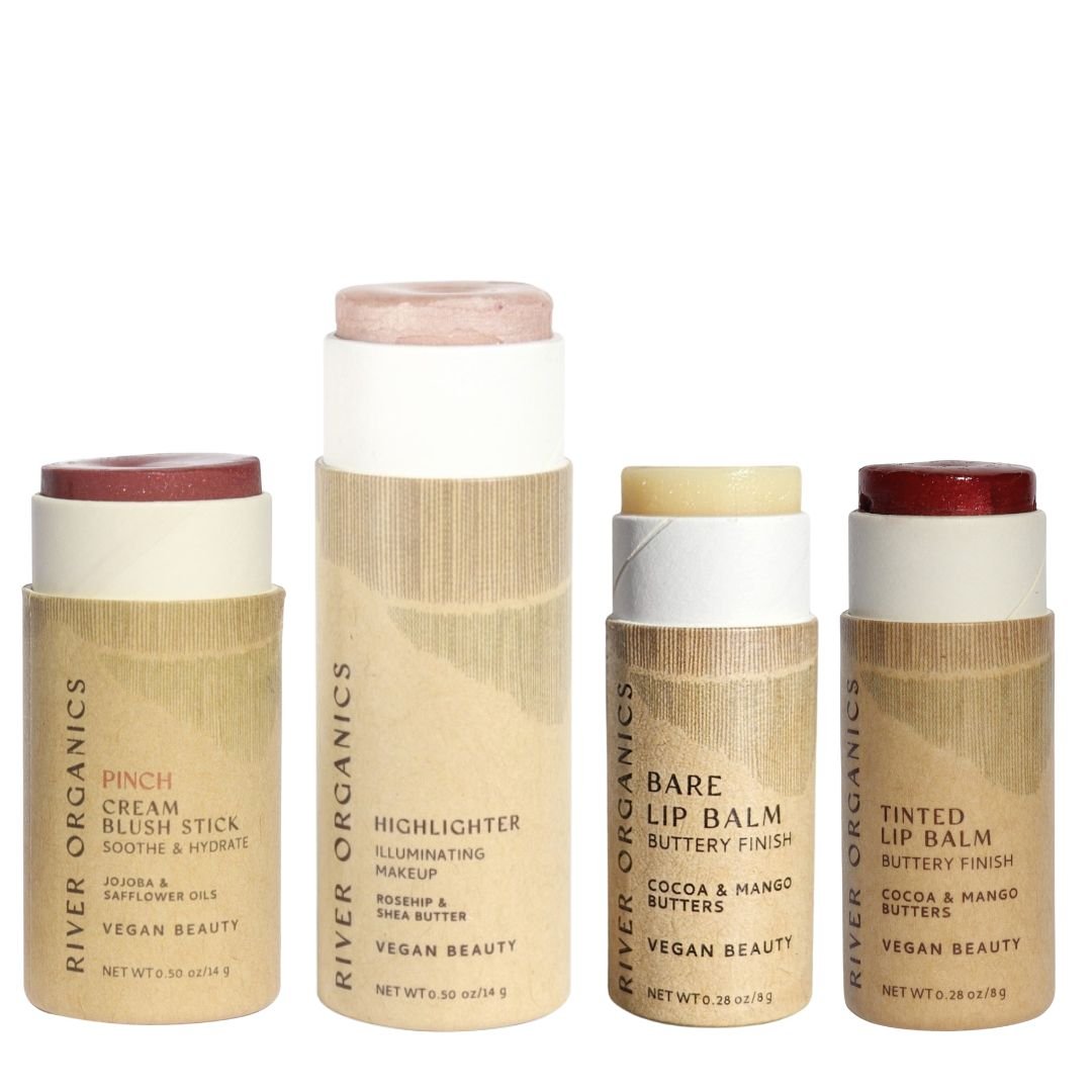 Four cylindrical Makeup Color Set by Tone sticks from River Organics stand upright, featuring blush, highlighter, and two lip products—all vegan, eco-friendly, and packaged in recyclable brown paper.