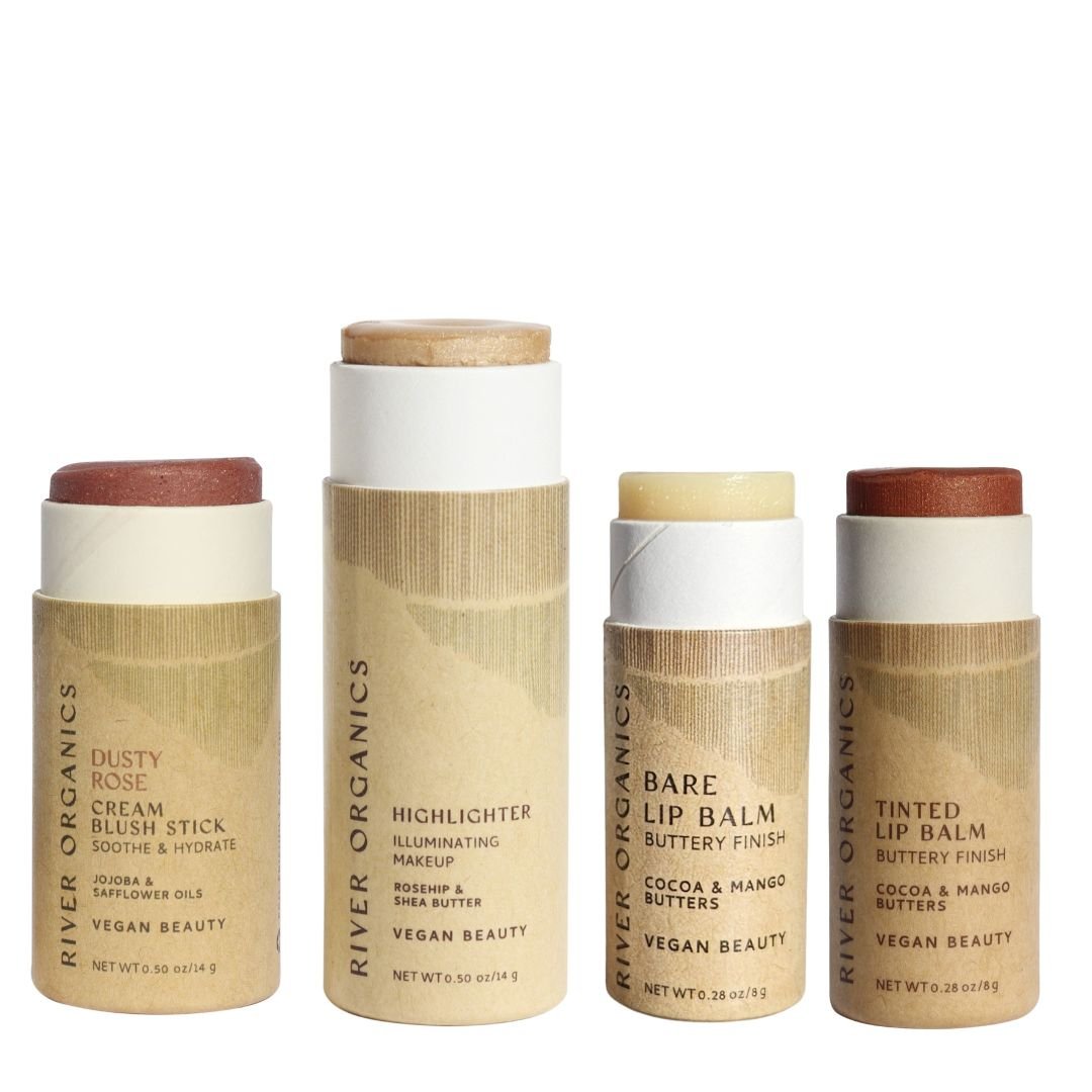Four upright tubes of River Organics' Makeup Color Set by Tone—Blush, Highlighter, and Two Lip Products—are displayed with lids off to reveal their colors and textures.