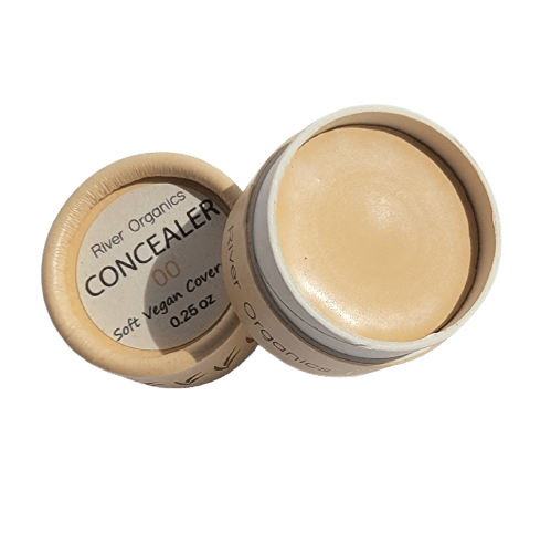 Open container of River Organics Lip + Concealer Set showing the creamy product inside and the label, which reads “Soft vegan cover, 0.25 oz.” The round container features a beige lid—perfect for adding to your clean beauty routine.