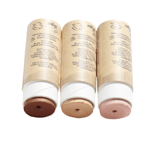 Three tubes of River Organics' Imperfect Highlighters & Bronzers, featuring eco-friendly and vegan packaging, are displayed horizontally. Each tube, labeled with text and capped in brown and pink shades, contains a different cream bronzer shade.