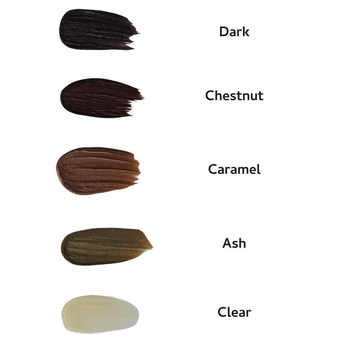 Five swatches of River Organics Brow Wax - Tame, Tint & Grow are labeled: Dark (deep brown), Chestnut (medium brown), Caramel (light brown), Ash (grayish brown), and Clear (off-white)—natural vegan shades for sustainable beauty.