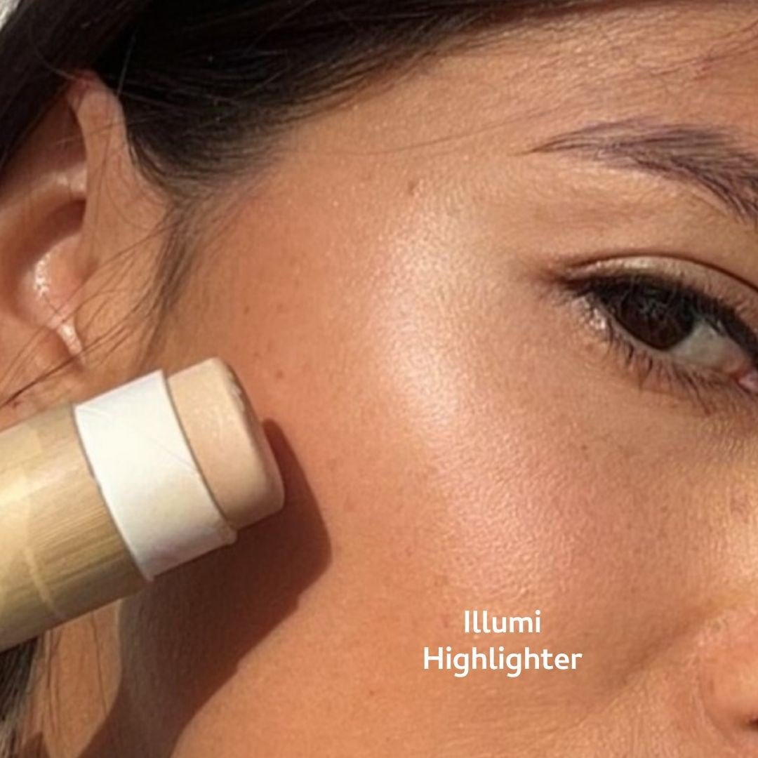A close-up of a cheek shows River Organics' Highlighter and Bronzer Set being applied for a glowy, natural look using non-toxic cosmetics. The product, labeled "Illumi Highlighter," is part of their makeup set collection.