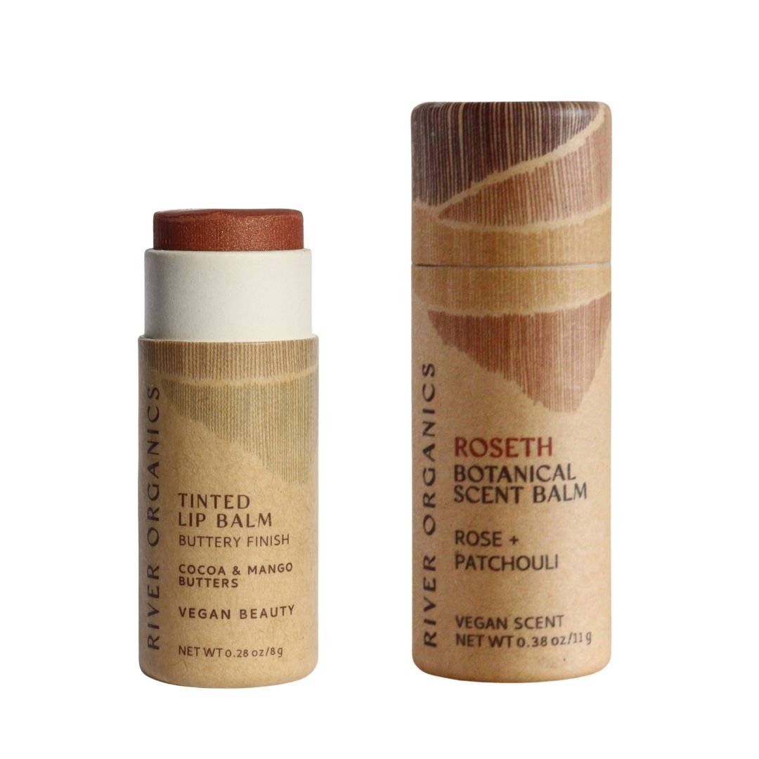 River Organics' Lip + Scent Balm Bundle includes a vegan tinted lip balm and a Roseth Botanical Ritual scent balm with rose and patchouli, both in eco-friendly cylindrical tubes with minimalist packaging.