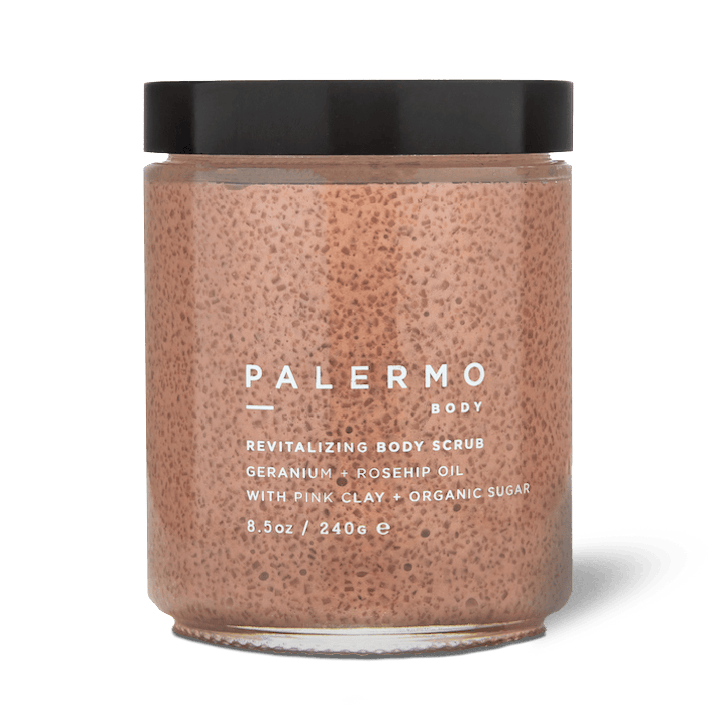 A clear jar with a black lid holds Palermo Body Revitalizing Body Scrub. The light brown, textured scrub features aromatherapeutic exfoliation with geranium, rosehip oil, French pink clay, and organic sugar; 8.5 oz (240 g).
