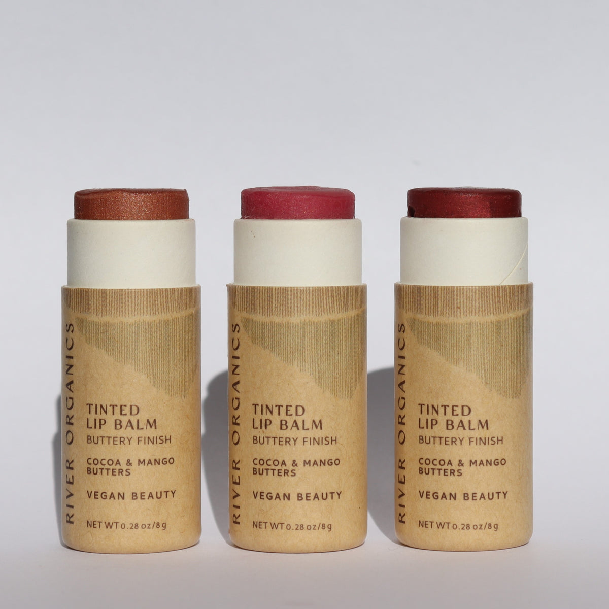 The River Organics Brow Wax + Blush + Lip Balm Bundle is shown upright in light brown packaging with black text, featuring bronze, pink, and red shades that pair perfectly with your favorite blush stick.