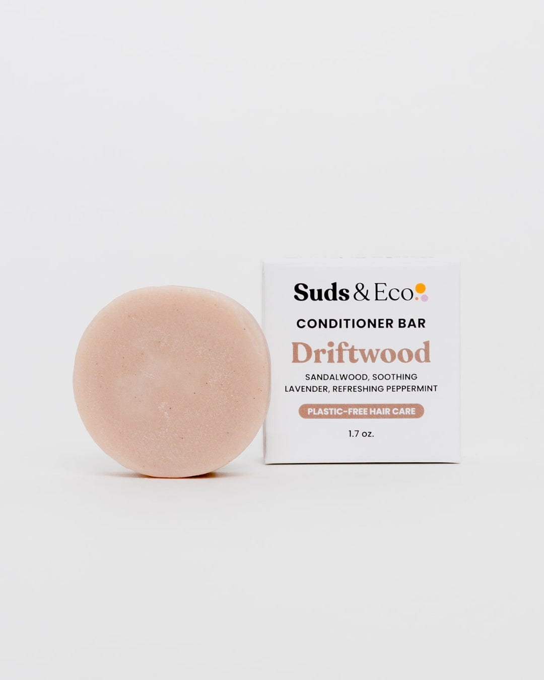 A round, beige Vegan Conditioner Bar from ZeroWasteStore.com sits beside its white “Conditioner Bar” box, featuring sandalwood, lavender, and peppermint scents—plastic-free, zero waste hair care in a 1.7 oz size.