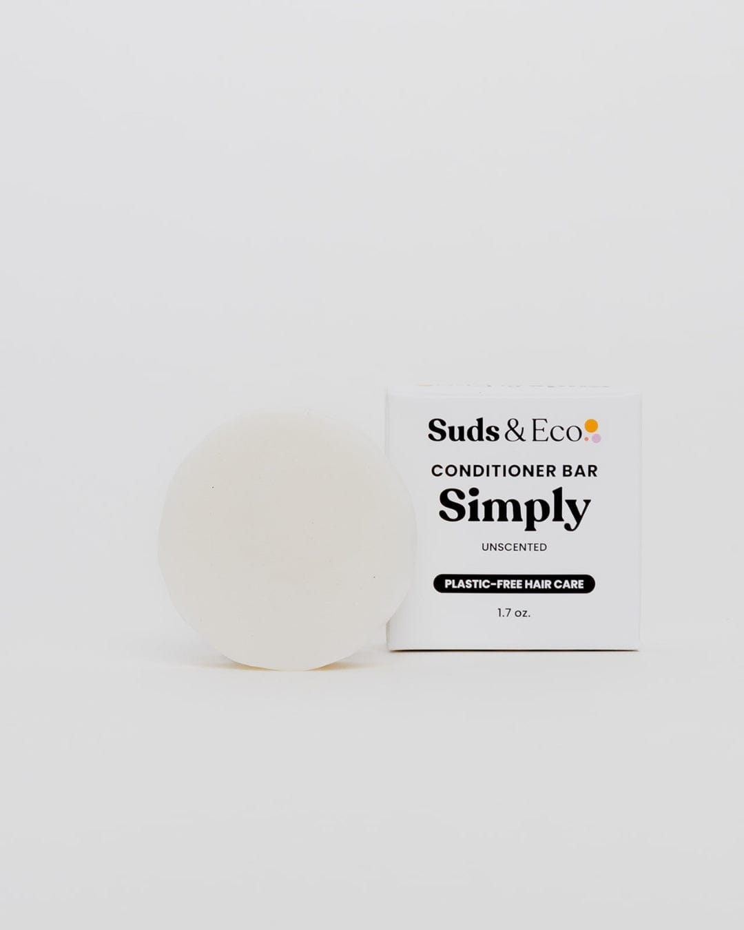 A round, white sulfate-free Conditioner Bar from ZeroWasteStore.com sits next to a box labeled "Conditioner Bar Simply Unscented, Plastic-Free Hair Care, 1.7 oz." on a plain white background—a great zero waste choice.