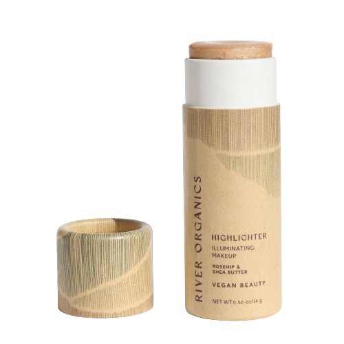 A capless cylindrical tube of River Organics' Imperfect Highlighters & Bronzers showcases the vegan makeup within. The eco-friendly packaging features a natural, wood-like design and reads "Illuminating Makeup, Rosehip & Shea Butter, Vegan Beauty.