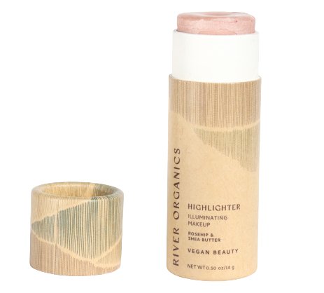 A tube of River Organics' Imperfect Highlighters & Bronzers, with its lid off, displays a label reading "Illuminating Makeup, Rosehip & Shea Butter, Vegan Beauty." The light beige tube is simply designed and contains a light pink vegan highlighter.