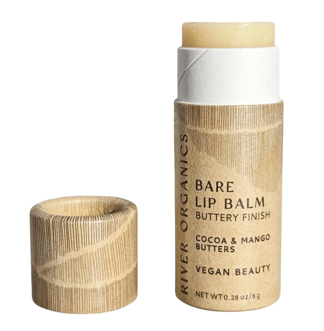 A tube of River Organics Bare Vegan Lip Balm with the cap off reveals the balm. The eco-friendly, brown textured packaging highlights cocoa and mango butters, vegan beauty, and a buttery finish.