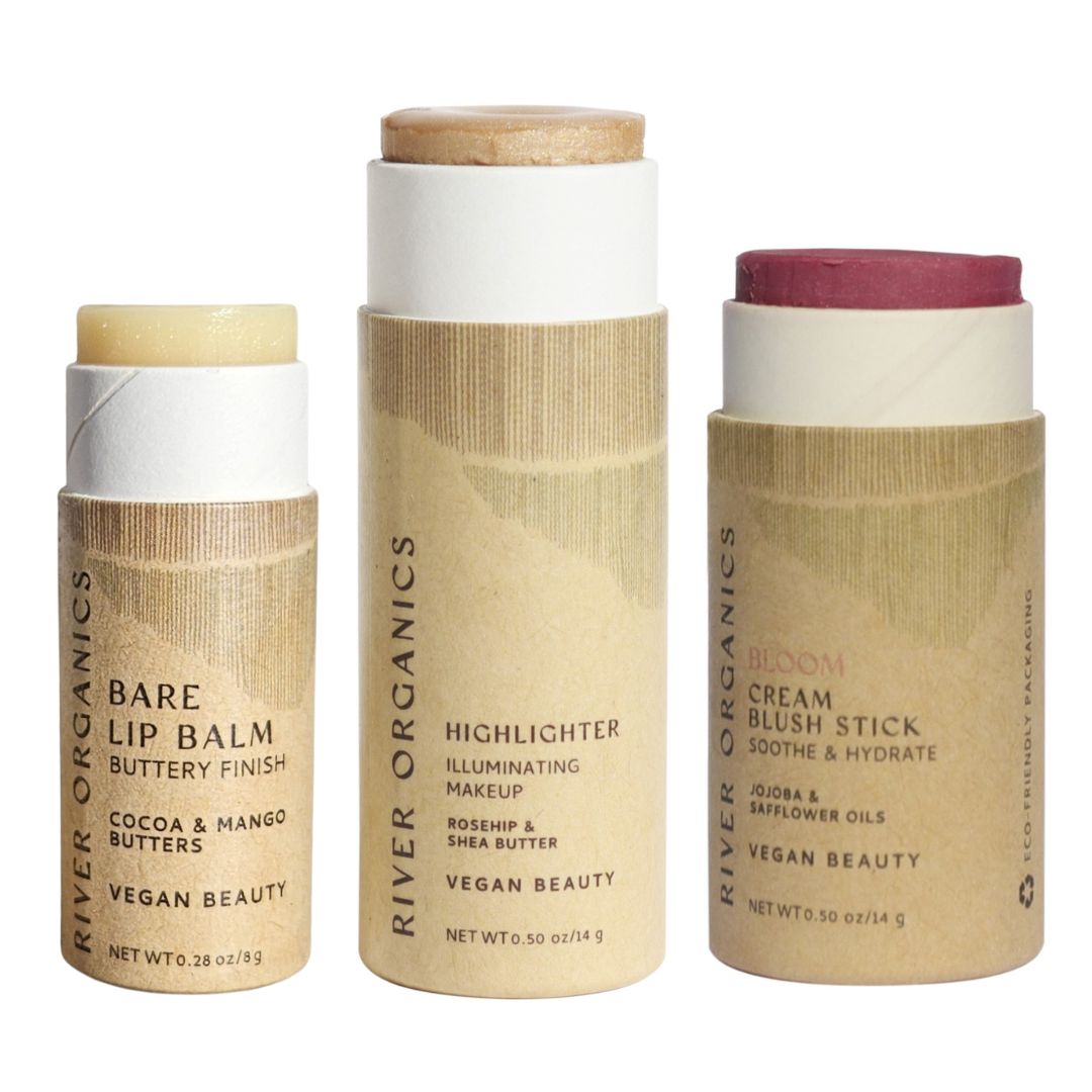 The River Organics Lip + Highlighter + Blush Set features three upright, cylindrical sticks with beige eco-friendly paper labels and minimalist, plastic-free packaging.