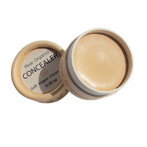 Open container of River Organics Lip + Concealer Set showing the creamy product inside and the label, which reads “Soft vegan cover, 0.25 oz.” The round container features a beige lid—perfect for adding to your clean beauty routine.