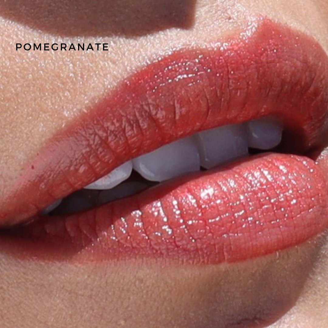A close-up of lips adorned with a glossy, deep red hue from River Organics' Lip Stain Sets, featuring a smooth finish. The top left corner flaunts the word "POMEGRANATE," highlighting the vibrant shade crafted with organic ingredients.