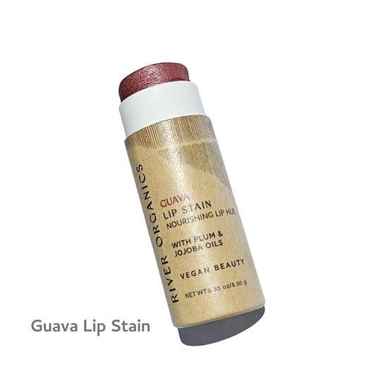 A tube of River Organics Vegan Lip Stains with a pinkish hue stands upright. The label emphasizes nourishing oils, is vegan, and spotlights this plastic-free lip stain. The product name and "Guava Lip Stain" are clearly visible on the packaging.