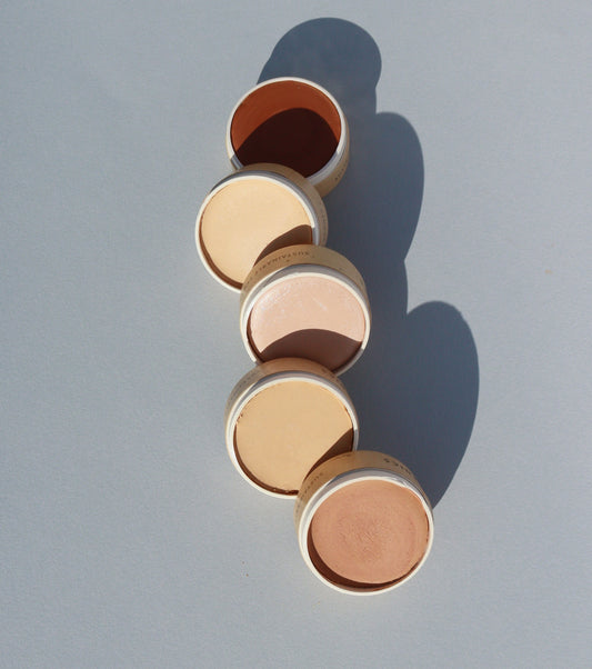 Five small, circular tins of River Organics Zero-Waste Vegan Concealer in varying skin tones arranged in a line.