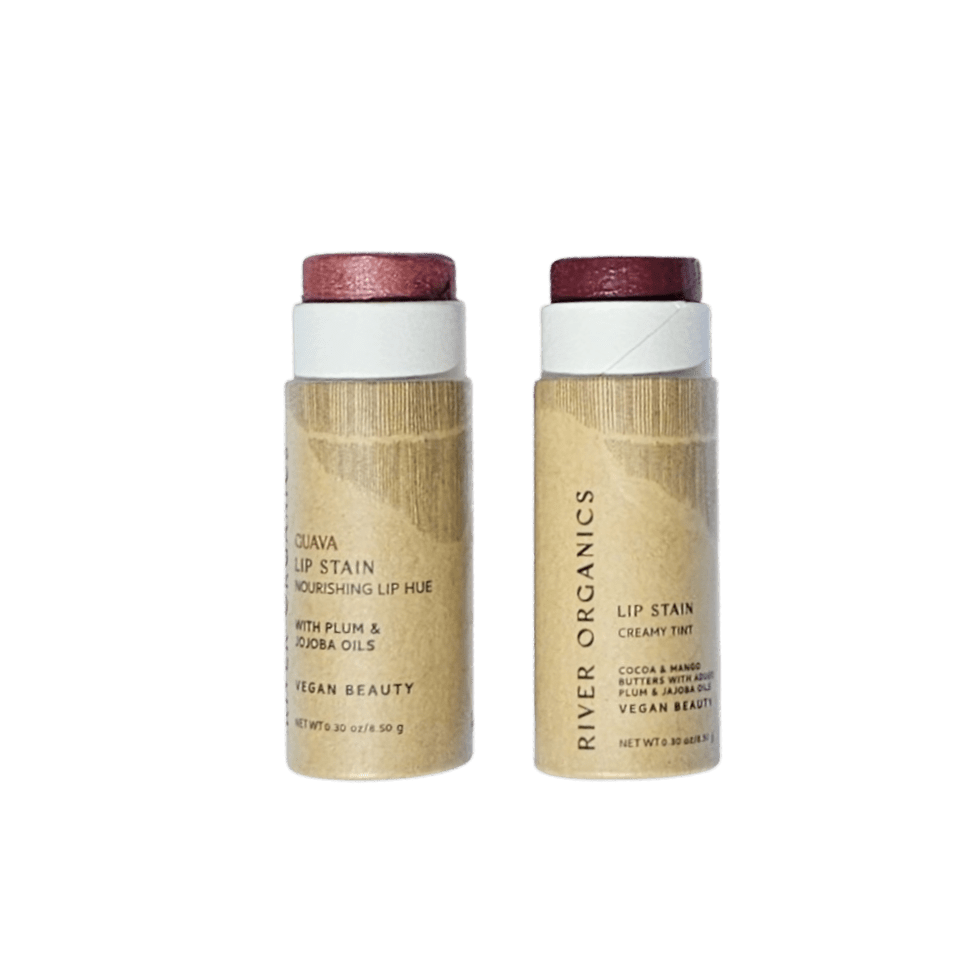 River Organics' Lip Stain Sets come in wooden tubes with reddish shades—one called "Guava" and the other "Creamy Tint"—standing upright against a plain black background.