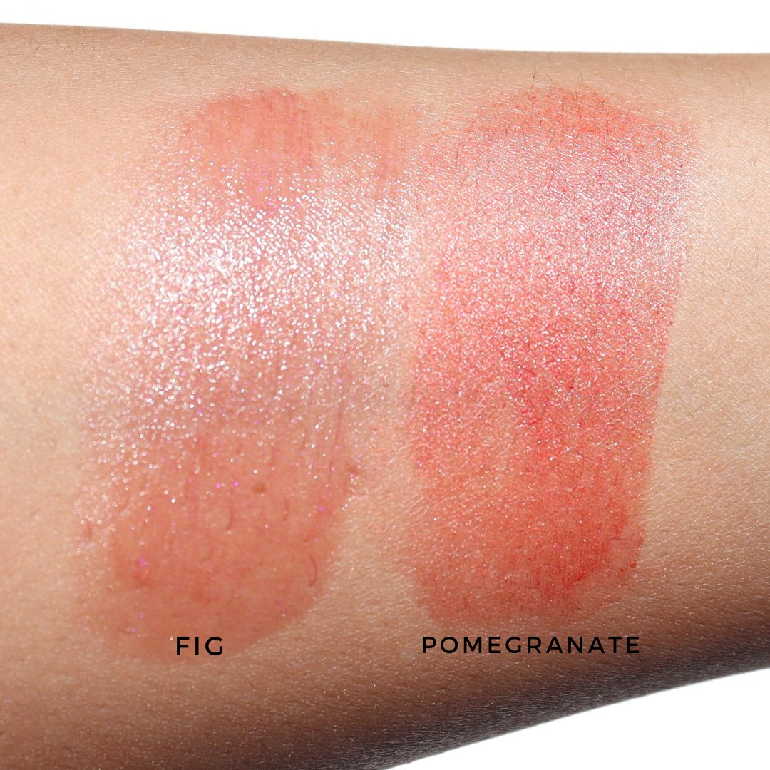 Swatches of River Organics' Lip Stain Set: "Fig" on the left—a shimmery light pink enriched with organic shea butter—and "Pomegranate" on the right, featuring a glossy red-pink hue.