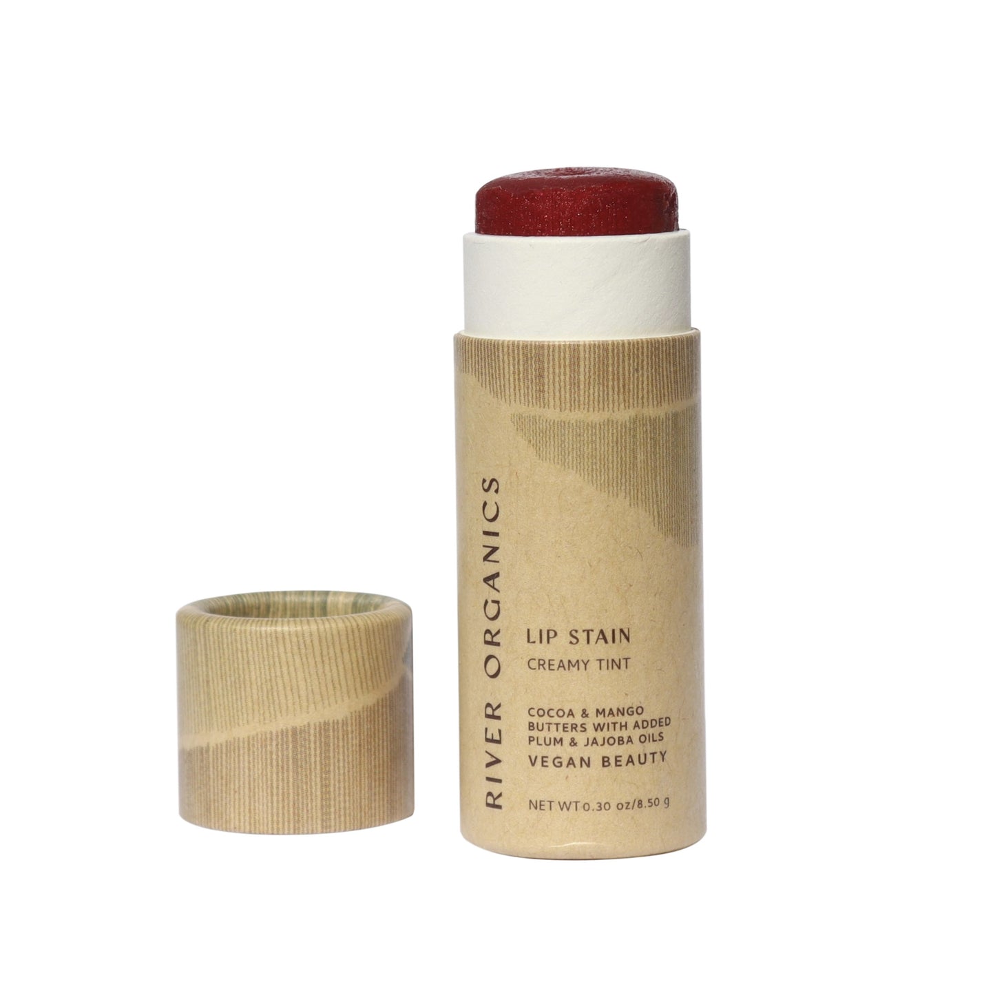 With the cap off, a tube of River Organics' Lip Stain Set in "Fig" + "Pomegranate" reveals a creamy red tint. The eco-friendly packaging showcases vegan ingredients like cocoa and mango butters, organic shea butter, plum, and jojoba oils—ideal for those seeking nourishing vegan lip care.