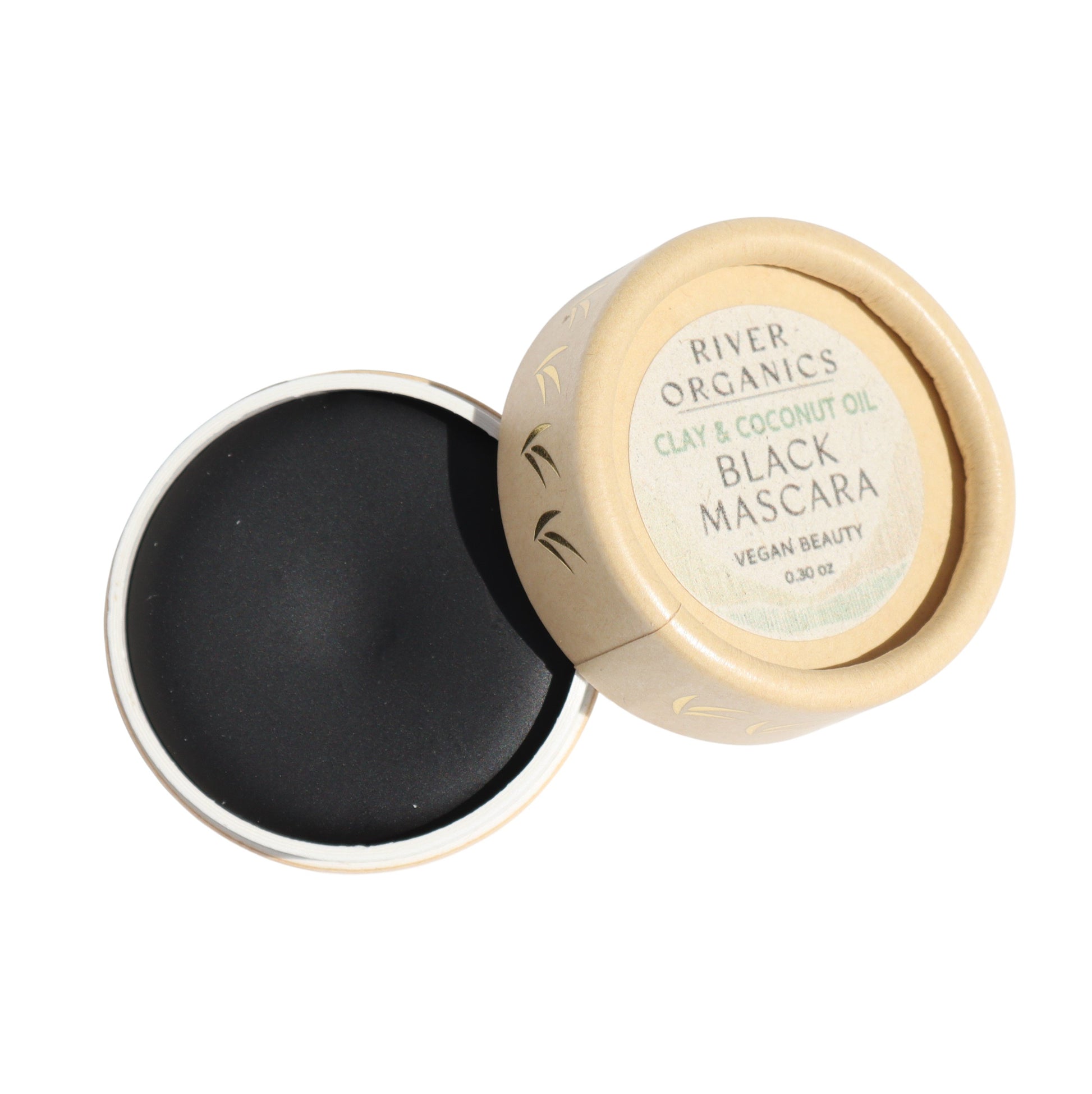 The round container of River Organics' Black Vegan Zero-Waste Mascara, featuring a lid with light brown labeling, slightly open to reveal the black mascara inside, is crafted with clay and coconut oil. Its simple, eco-friendly design suits those embracing zero-waste beauty ideals.