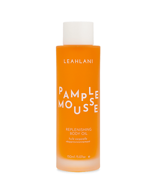 A 150 ml (5 fl oz) bottle of LEAHLANI Pamplemousse Replenishing Body Oil, featuring orange liquid, white text, a white cap, and infused with moisturizing tropical oils plus Vitamin C.