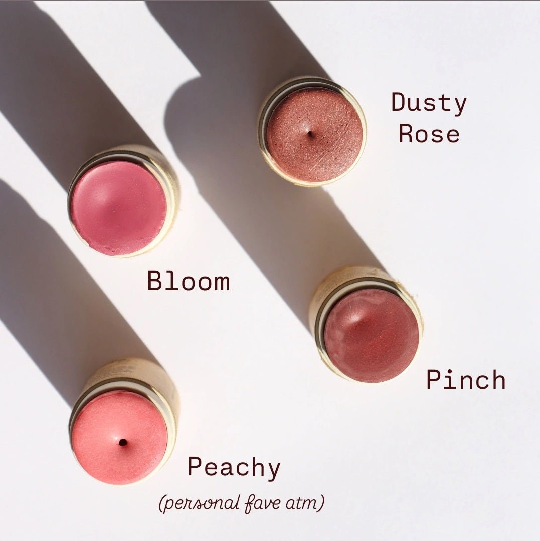 Four Imperfect Creamy Vegan Blush Sticks by River Organics are arranged diagonally, highlighting shades: Dusty Rose, Bloom, Pinch, and Peachy. "Peachy" is a current favorite. Enjoy zero-waste beauty with each organic ingredient blush. Shadows gently fall to the left.
