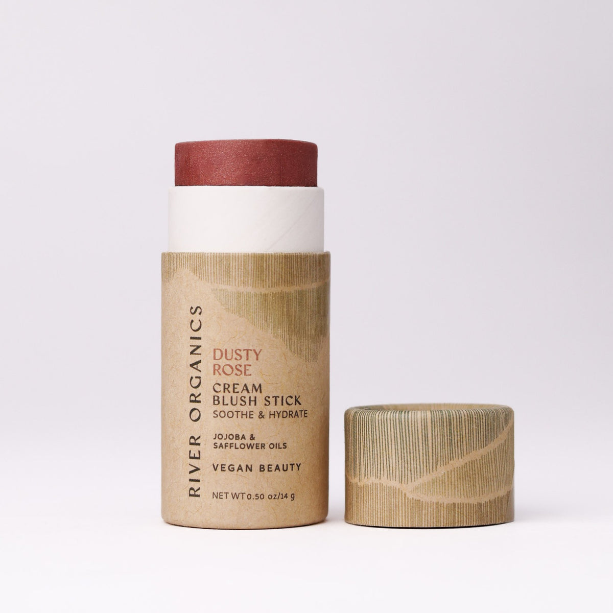 A dusty rose-colored River Organics Natural Cream Blush Stick in a cardboard tube, positioned beside its matching cap.