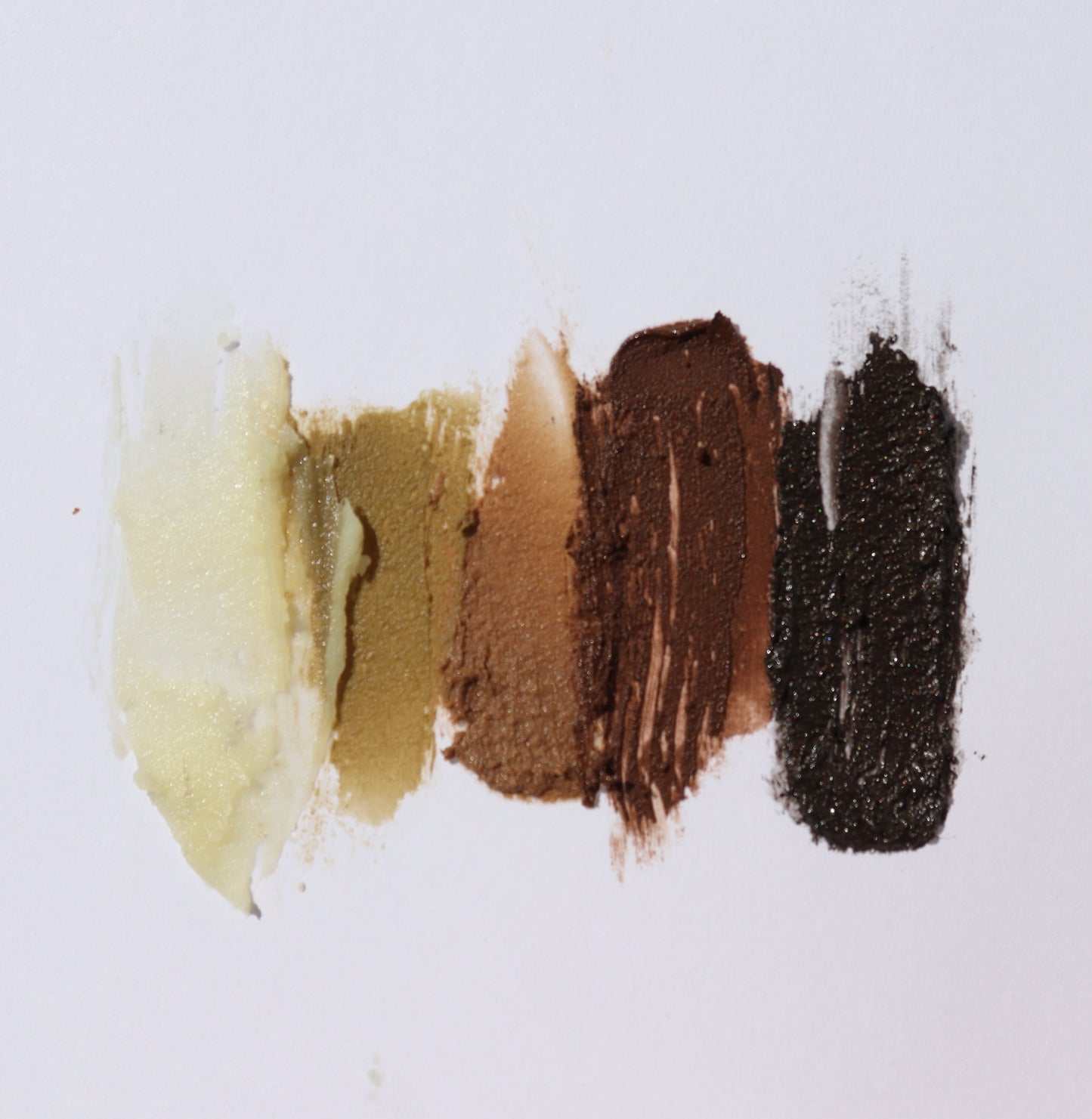 Five swatches of River Organics Brow Wax & Growth Serum - All Colors, in shades from light beige to deep brown and black, are streaked vertically on a white background.