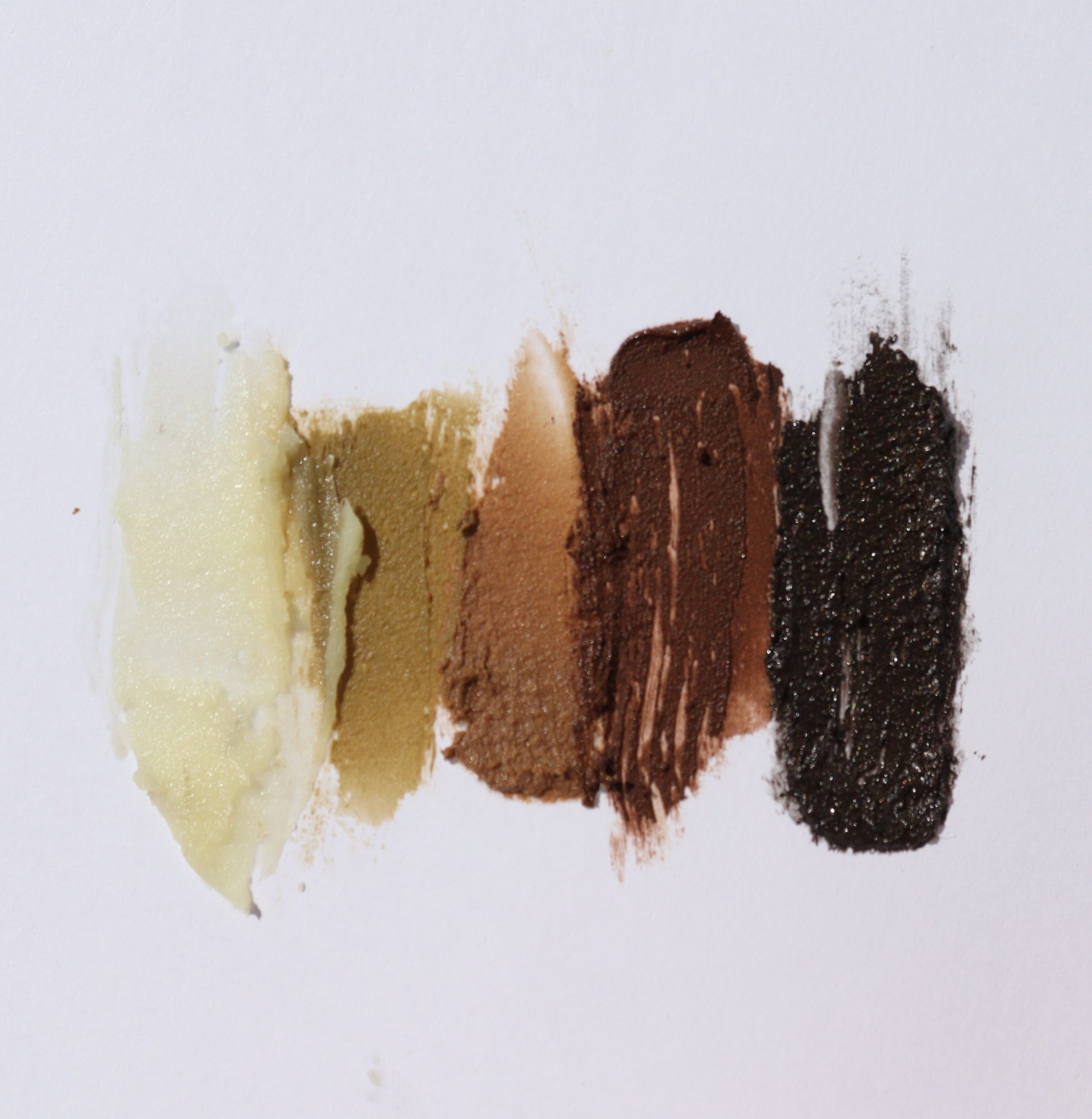 Five swatches of River Organics Brow Wax & Growth Serum - All Colors, in shades from light beige to deep brown and black, are streaked vertically on a white background.