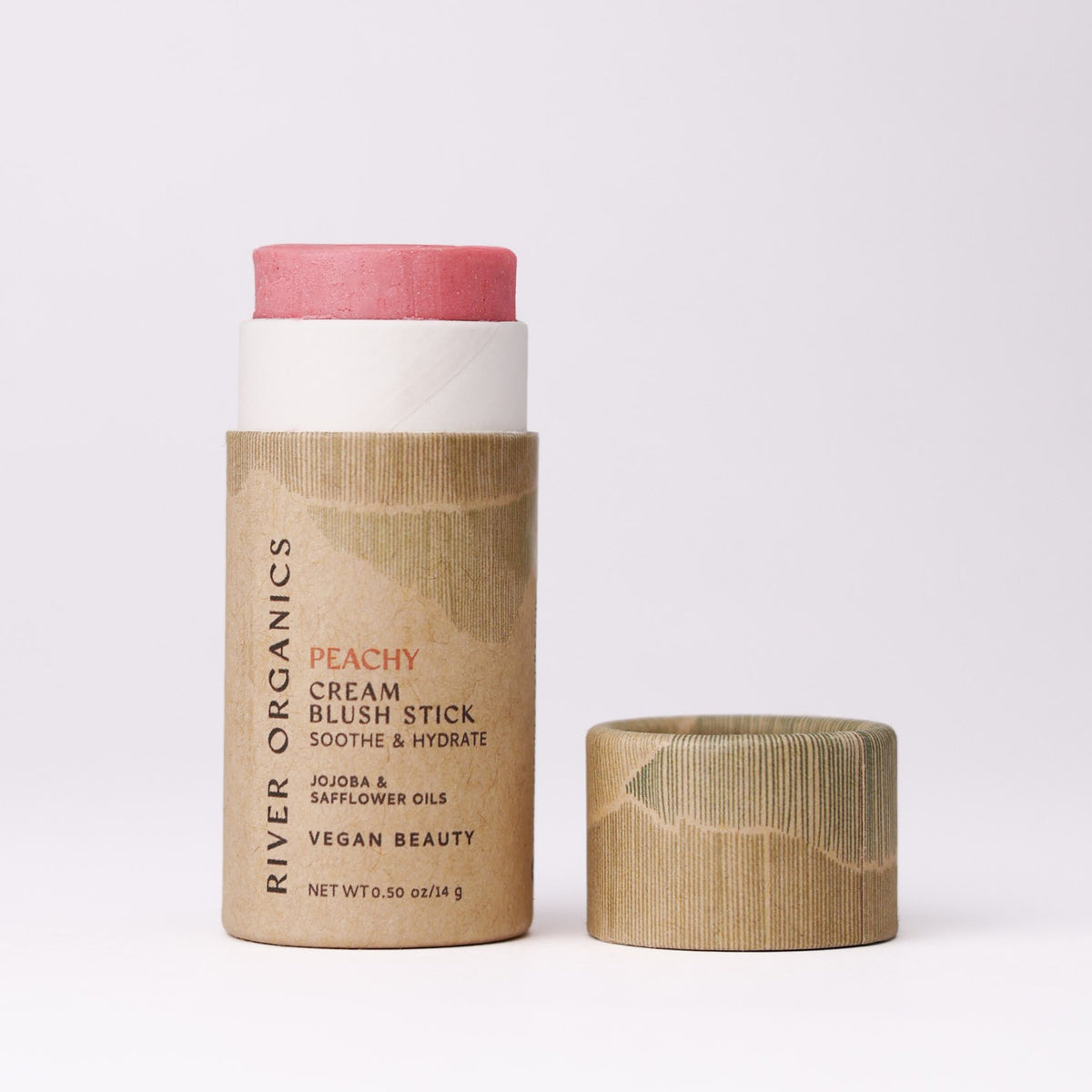 A pink-tinted River Organics Natural Cream Blush Stick in a plastic-free cardboard tube with the cap removed.
