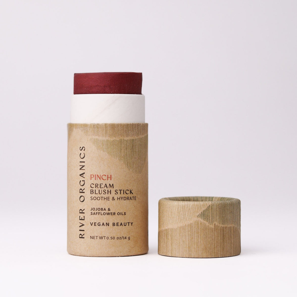 A River Organics Natural Cream Blush Stick in a red pigment inside a cardboard tube, shown next to its matching cap.