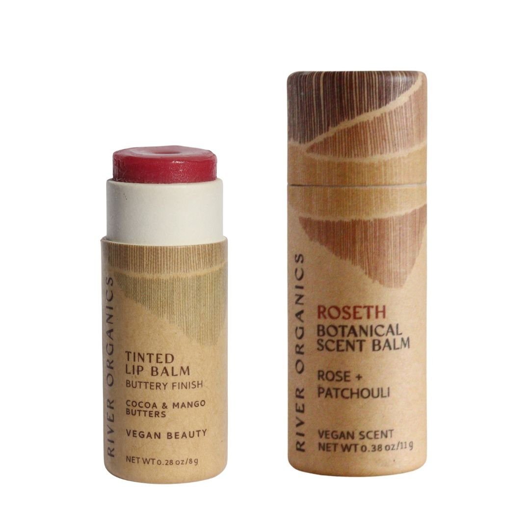 River Organics Lip + Scent Balm Bundle: two eco-friendly cardboard tubes—one partially open vegan lip balm showing red balm, and one closed tube labeled “Roseth Botanical Scent Balm: Rose + Patchouli.”.