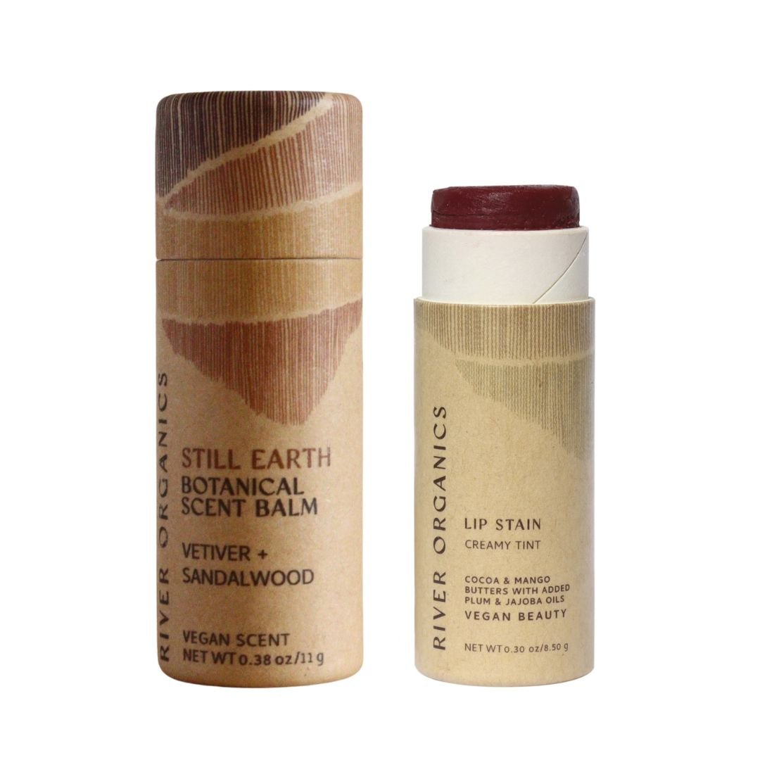 The River Organics Lip + Scent Balm Bundle features two cylindrical tubes in minimalist beige packaging—one closed scent balm and one open vegan lip stain with a red tint—perfect for your daily botanical ritual.