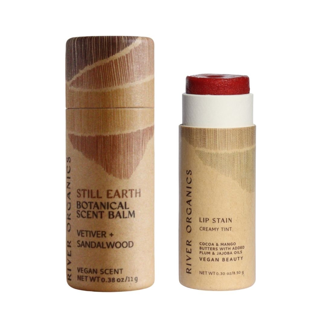 River Organics Lip + Scent Balm Bundle: two cylindrical tubes on a white background—one Vetiver + Sandalwood botanical ritual scent balm, and one red-tinted vegan lip balm—both in eco-friendly packaging.