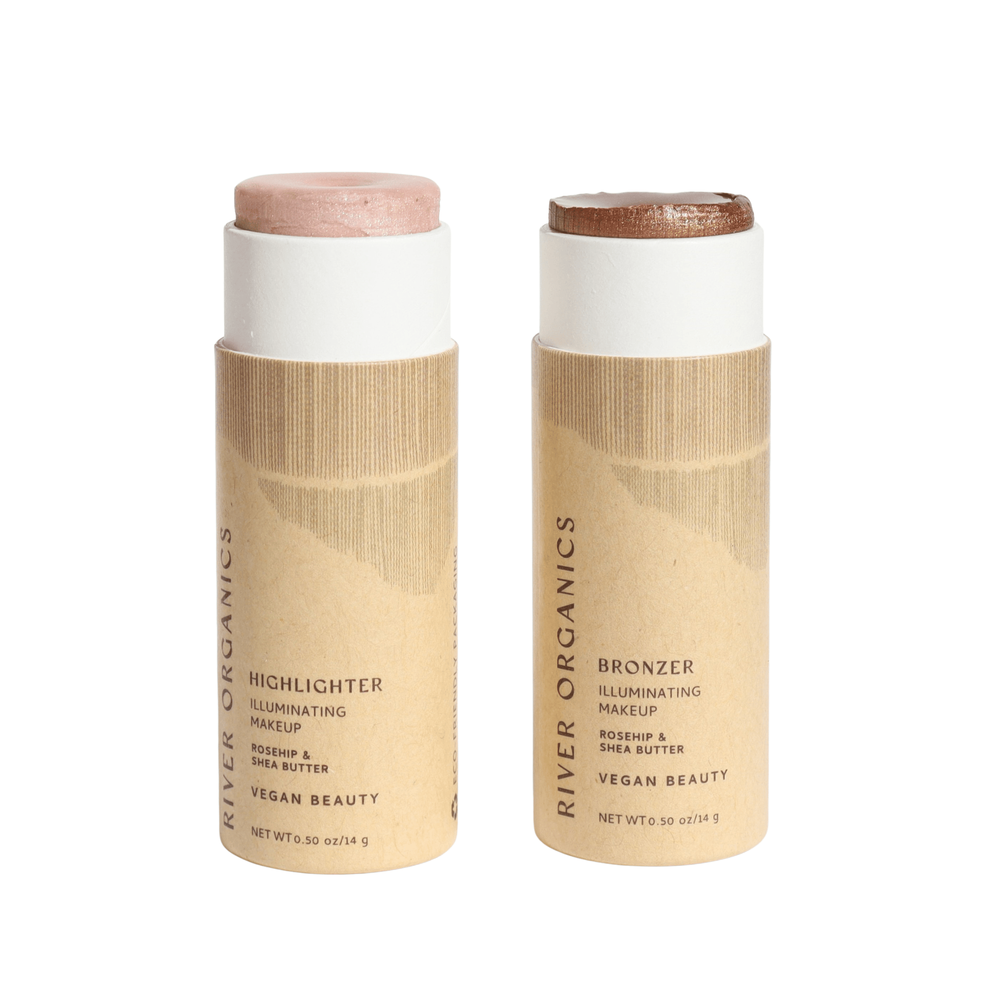 Two cylindrical, upright makeup sticks are in beige cardboard tubes from River Organics. The left is a pink highlighter and the right is a bronze bronzer. Both products are vegan, long-wearing, and made with non-toxic ingredients.