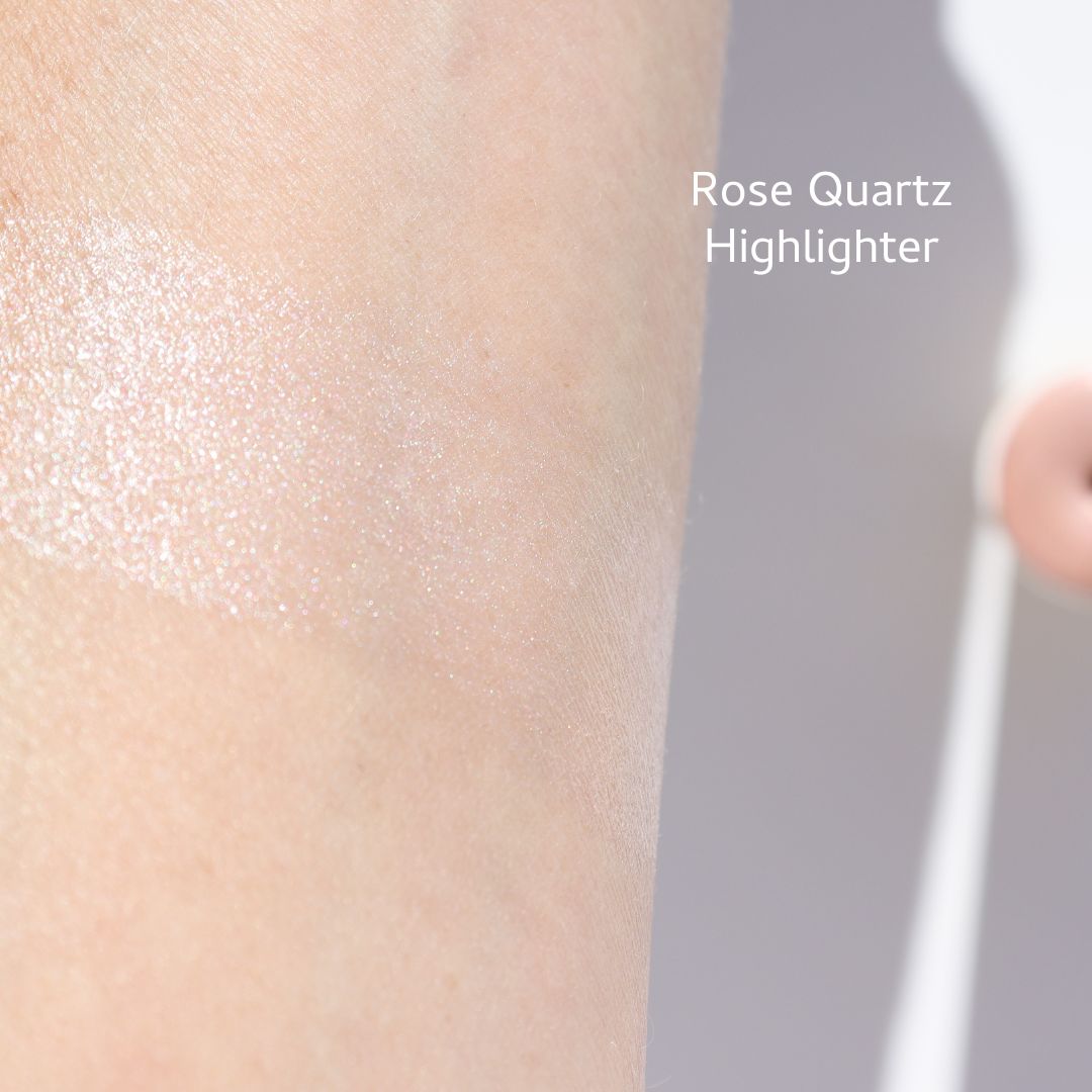 Close-up of an arm with a swatch of River Organics' shimmery "Rose Quartz" from their Highlighter and Bronzer Set, reflecting light for a sparkling effect with its long-wearing formula.