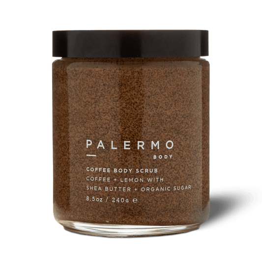 A clear jar with a dark lid labeled "Palermo Body Coffee Body Scrub" holds a brown exfoliating scrub made with coffee, lemon, shea butter, and organic sugar. The label shows the weight as 8.5 oz (240 g).