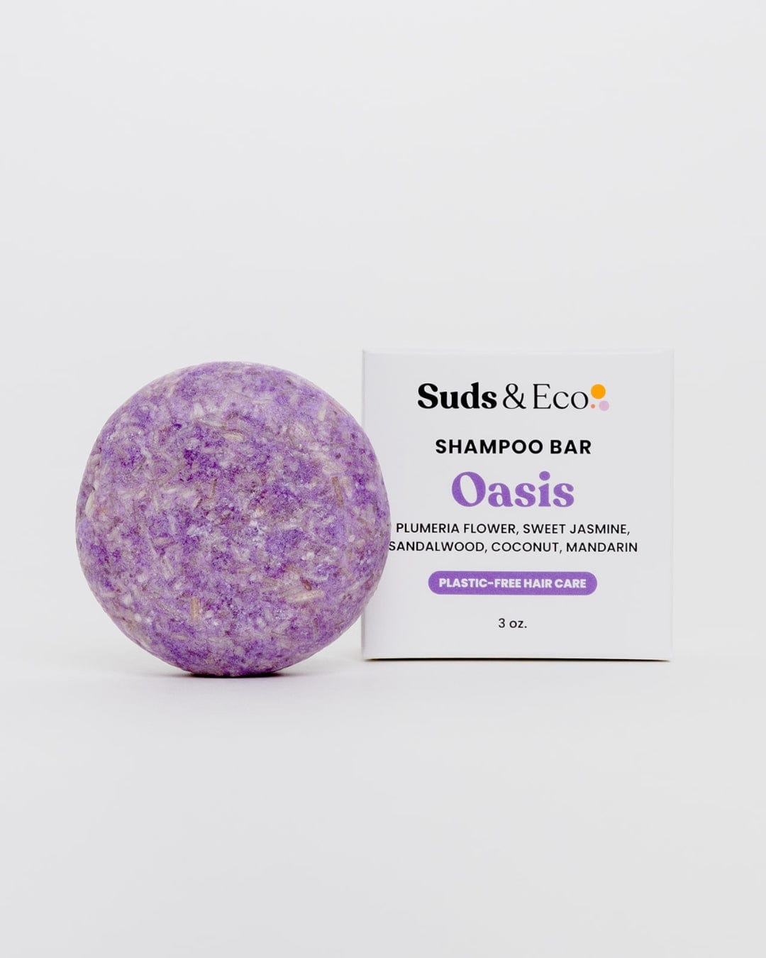 A round, purple ZeroWasteStore.com Shampoo Bar sits beside its white box, labeled "Shampoo Bar," featuring vegan-friendly scents of plumeria, jasmine, sandalwood, coconut, and mandarin.