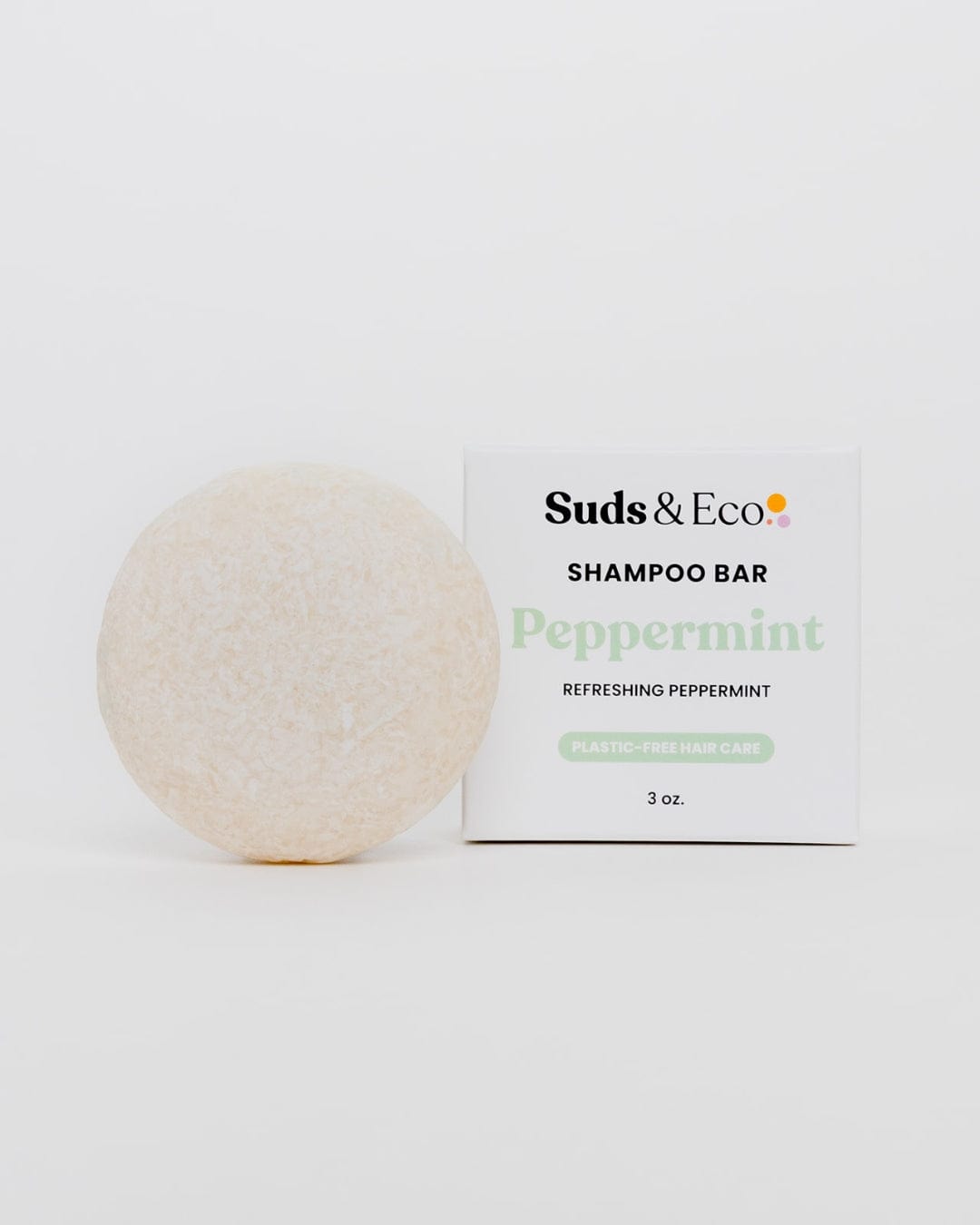 A round, off-white vegan shampoo bar from ZeroWasteStore.com is pictured next to a white box labeled "Shampoo Bar" on a plain white background.