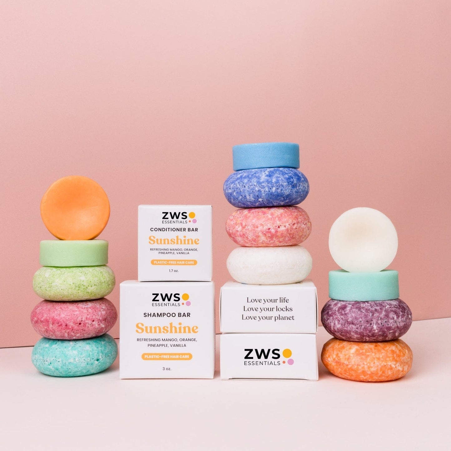 A colorful stack of round Shampoo & Conditioner Bar Duo by ZeroWasteStore.com sits on a pink background, with white packaging labeled "Sunshine" and "Love your locks, Love your planet" for a zero waste haircare routine.