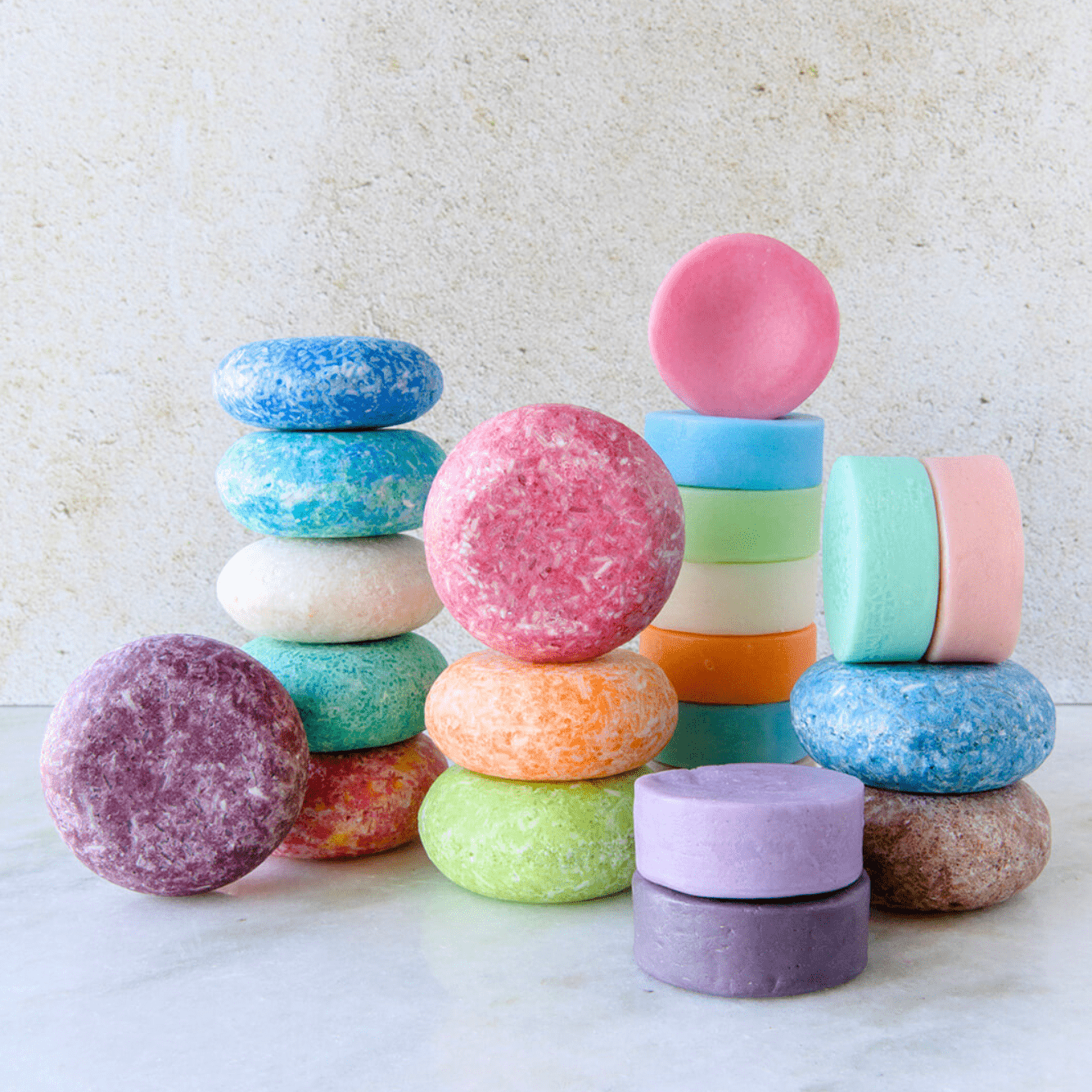 Neatly stacked on a light surface, ZeroWasteStore.com’s Shampoo & Conditioner Bar Duo features vibrant and pastel-colored vegan bars—an eye-catching, zero waste haircare solution arranged against a neutral background.