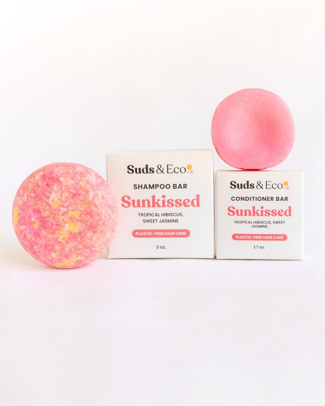 Two pink Shampoo & Conditioner Bars from ZeroWasteStore.com are shown with their boxes labeled "Shampoo & Conditioner Bar Duo." Vegan and zero waste, they feature tropical hibiscus and sweet jasmine scents for eco-friendly hair care.