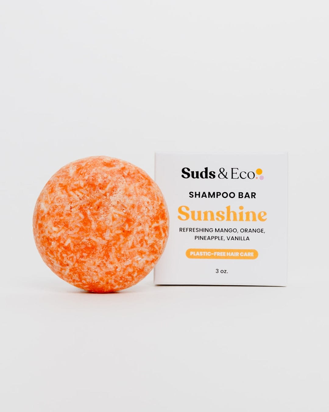 A vibrant orange and white marbled Shampoo Bar from ZeroWasteStore.com rests next to its box, exuding mango, orange, pineapple, and vanilla scents. This vegan bar is SLS-free and offers a zero-waste, plastic-free hair care experience.