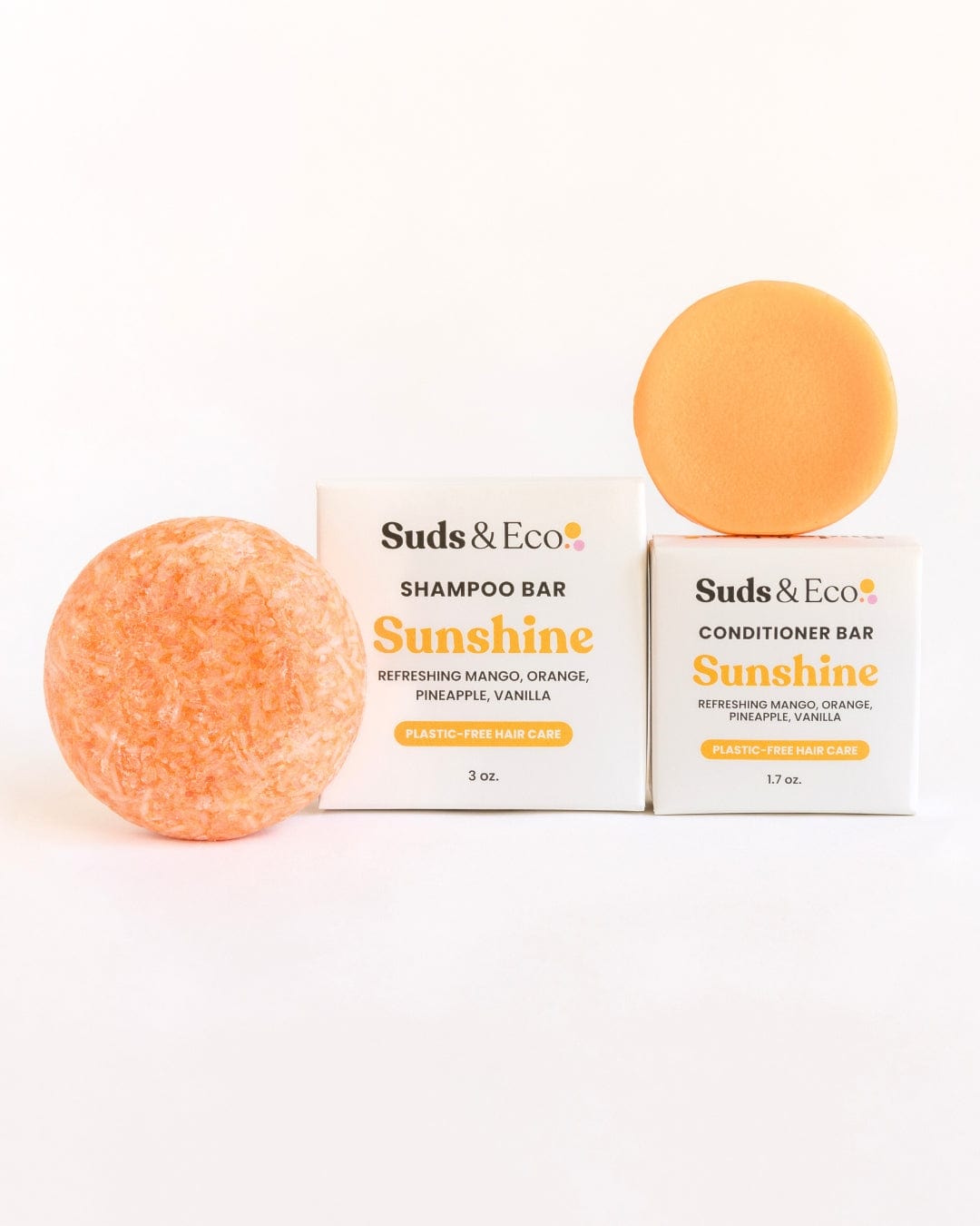 Two orange bars—one textured, one smooth—are shown in front of white boxes labeled "Shampoo & Conditioner Bar Duo" from ZeroWasteStore.com. Both are zero waste, vegan, and scented with mango, orange, pineapple, and vanilla.