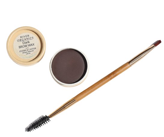 An open container of Tinted Vegan Eyebrow Wax | Dark is shown with its lid nearby, labeled "River Organics Tinted Vegan Eyebrow Wax | Dark." This vegan brow wax offers a natural brow color. A dual-ended brush with a spoolie on one end and an angled brush on the other is positioned next to the containers.