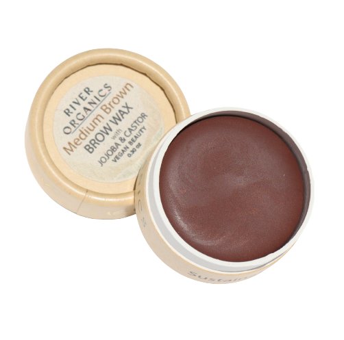 A round container of Tinted Vegan Eyebrow Wax | Medium Brown from River Organics Skincare is shown. The beige container, with the lid partially open, reveals the tinted eyebrow wax inside. The label on the lid indicates it's made with jojoba and castor oils and is both vegan and cruelty-free certified.