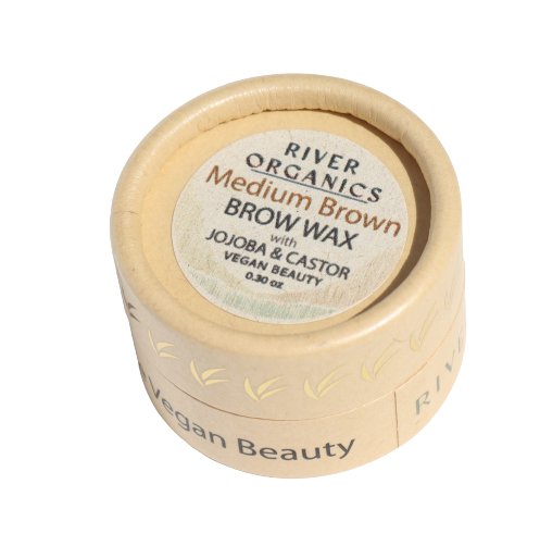 A round, beige container labeled "River Organics Skincare Tinted Vegan Eyebrow Wax | Medium Brown" with "Jojoba & Castor" and "Vegan Beauty" written below. The 0.30 oz of tinted eyebrow wax inside boasts a simple, natural design with earthy tones and is proudly cruelty-free certified.