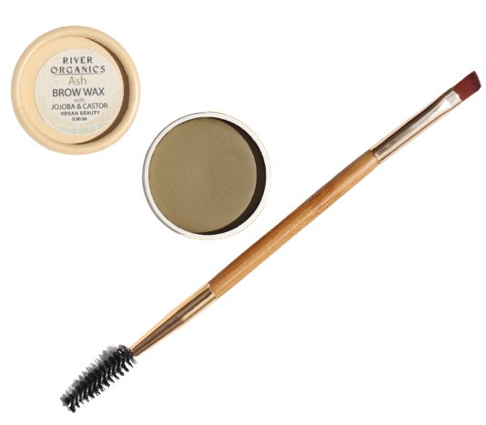 Image shows an open container of River Organics Tinted Vegan Eyebrow Wax | Ash with the lid placed nearby, revealing a greenish-gray tinted brow wax inside. Also displayed is a dual-ended eyebrow brush with a spoolie on one end and an angled brush on the other. The product is eco-friendly and vegan certified.